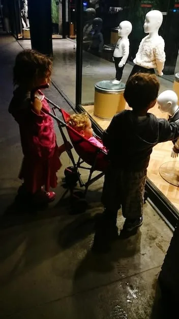 A bustling scene inside an underground fashion trade show, with diverse attendees examining unique, handcrafted garments on display. The lighting is moody, reflecting an independent, artistic vibe.