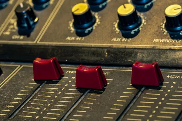 A close-up shot of a mixing board in a DIY music venue. The board is labeled with colorful tape, and various knobs and sliders are being adjusted by a sound engineer. The focus is on the technical equipment and the hands operating it.
