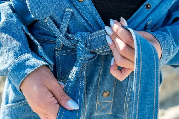 A close-up shot of a person's hands carefully cutting and sewing repurposed denim fabric to create a patchwork design. The work area is filled with various tools and materials, showing the process of transforming discarded items into high-fashion pieces.