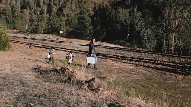 A dramatic photograph displaying a group of environmental activists blockading a logging road in a dense forest, with some members chaining themselves to heavy machinery. The scene conveys a sense of urgency and determination, highlighting the lengths to which these activists are willing to go to protect endangered ecosystems. The contrast between the natural environment and the industrial equipment emphasizes the conflict at the heart of the dark ecology movement.