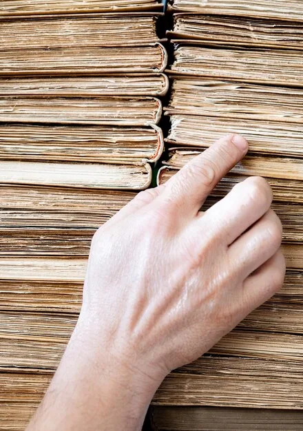 A close-up of an artist's hands meticulously organizing a stack of receipts and invoices. The focus is on the detail-oriented nature of managing financial records for tax purposes.