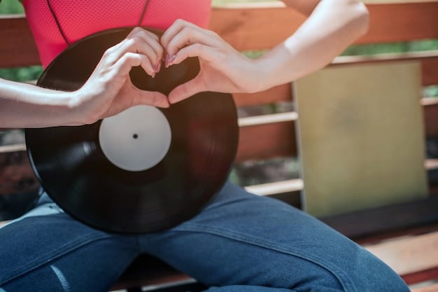 A close-up photograph of a person's hands gently placing a vinyl record onto a turntable in a dimly lit room, emphasizing the tactile and intimate experience of listening to vinyl.