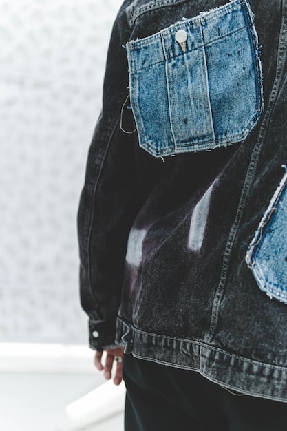 A close-up shot of a denim jacket covered in patches made from recycled and upcycled materials, including scraps of fabric, buttons, and pins. The jacket has a distressed look, with frayed edges and visible stitching, highlighting the punk aesthetic.