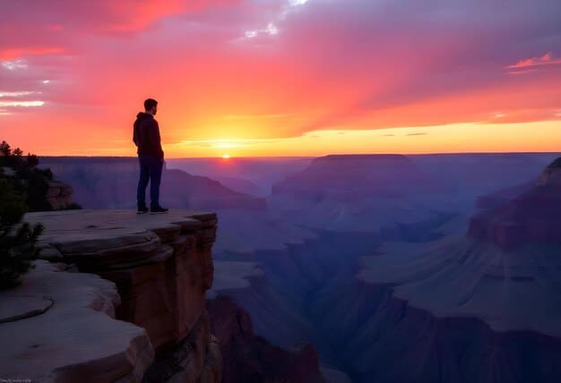 A person standing at the edge of a cliff, overlooking a vast canyon at sunset. They are silhouetted against the colorful sky, with their arms raised in a gesture of reverence. The image conveys a sense of awe and connection with nature.