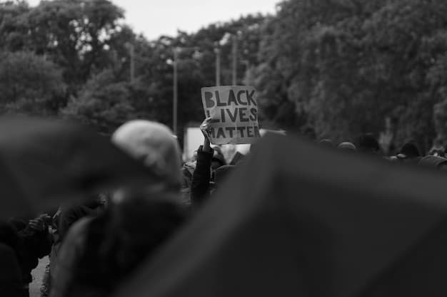 A black and white photo depicting a group of protestors from the Black Lives Matter movement marching down a street in a US city. They are holding signs and chanting slogans. The image highlights the determination and solidarity of the protestors.
