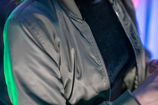 A close-up shot of a deconstructed streetwear jacket. It features visible seams, raw edges, and mismatched fabric panels in muted tones. The jacket also incorporates functional elements like oversized pockets and adjustable straps.