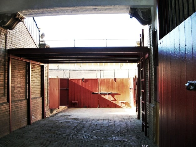 An exterior shot of a potential DIY music venue location – a converted warehouse in an up-and-coming urban neighborhood. The building has graffiti art on the walls and a simple sign indicating 