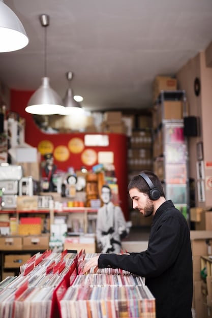 A shot of an independent record store, with customers browsing through vinyl records. The store is well-lit and inviting, with a diverse selection of albums on display.