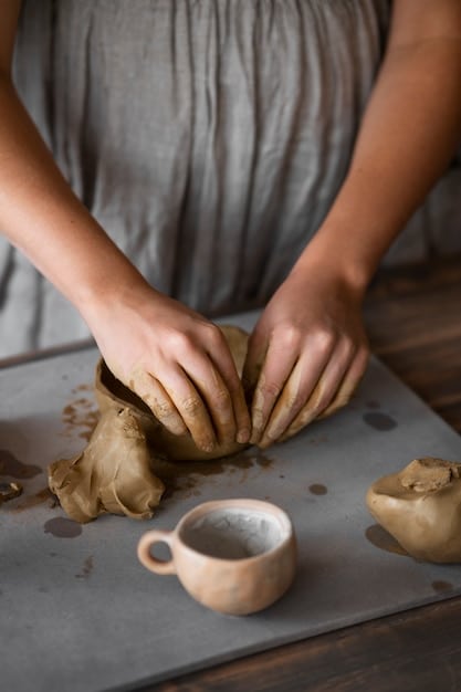 Close-up of hands working on a pottery wheel, shaping clay. The focus is on the tactile nature of the craft and the concentration of the artist, highlighting the mindful aspect of analog activities.