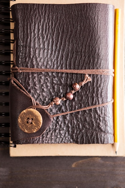 A close up shot of a intricately designed leather-bound journal, open to a page filled with handwritten notes, sketches of fantastical creatures, and pressed flowers. The journal is placed on a wooden table surrounded by various items such as vials, quills, and a wax-sealed letter, suggesting a character immersed in creating their own lore.