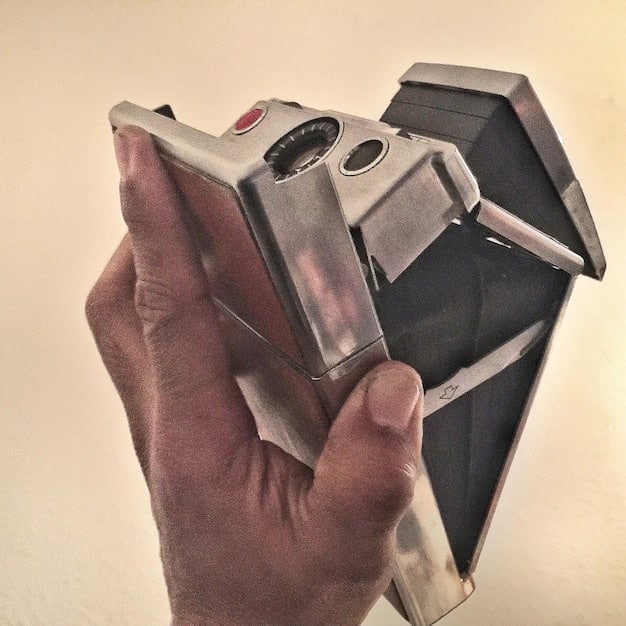 A close-up shot of a person's hands carefully threading film into a vintage camera. The focus is on the intricate mechanics of the camera and the tactile sensation of handling the film. The image emphasizes the deliberate and mindful nature of analog photography.