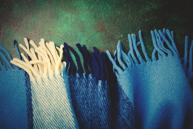 A close-up shot of deconstructed denim jeans featuring a patchwork design with various shades of blue denim. Intentional distressing and exposed stitching are visible, highlighting the unique details of the garment.