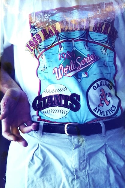 A close-up of a vintage punk rock t-shirt with a faded band logo and distressed edges, laid out on a wooden table with a measuring tape and a magnifying glass. The scene conveys a sense of authentication and detailed inspection.