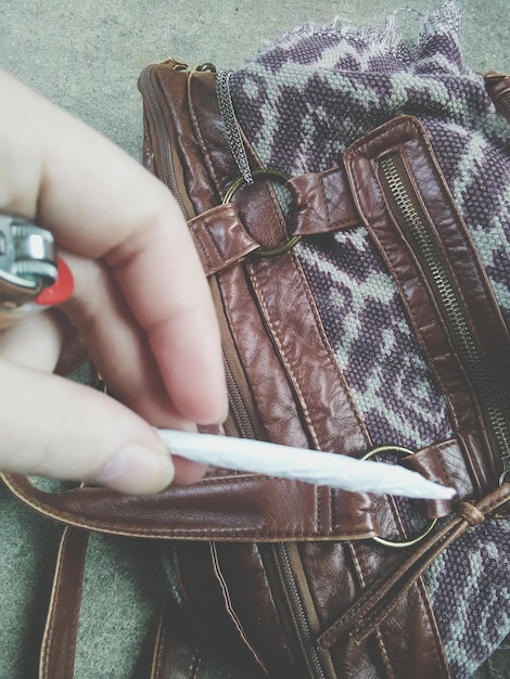 Close-up shot of a deconstructed handbag made from recycled leather scraps, featuring exposed stitching, asymmetrical pockets, and a chain strap.