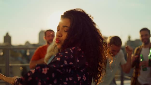 A diverse group of young adults enthusiastically attending an outdoor live music concert, with sun setting in the background.