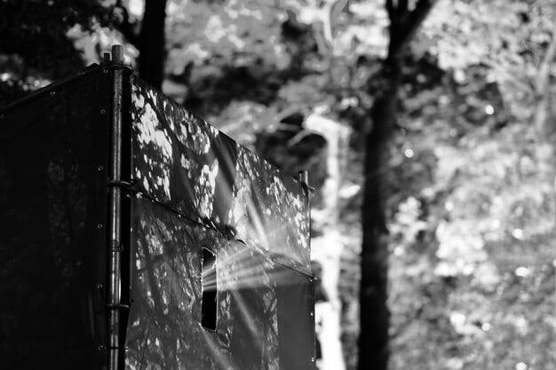 A close-up of a large-format pinhole camera, weathered and with an abstract urban landscape blurred in the background, signaling experimental photography.
