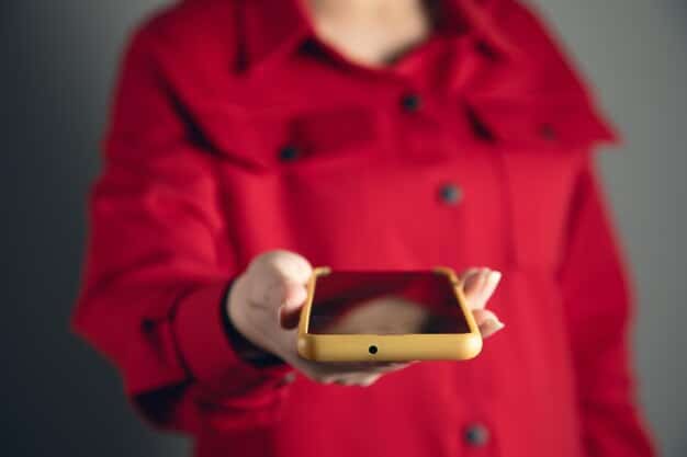 A close-up shot of hands scrolling through a smartphone, with a blurred background showing various social media interfaces, suggesting the pervasive nature of online influence and potential radicalization.