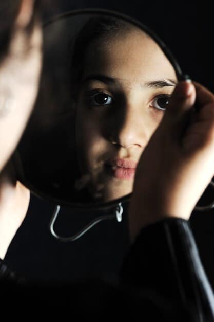 A close-up shot of a singer's face partially obscured by shadow, with intense, reflective eyes, conveying deep emotion and mystery in a dark, atmospheric setting.