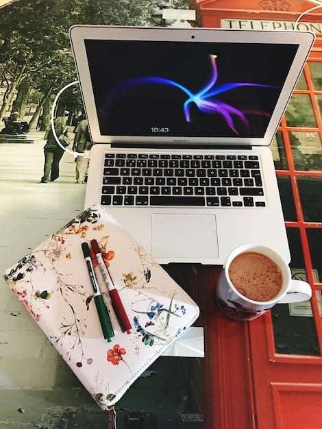 A detailed flat lay of a graphic designer's desk with a laptop displaying album art mockups, color swatches, legal documents, and a coffee mug, representing the technical and legal aspects of design.