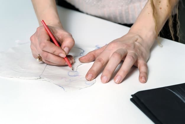 A close-up of an artist's hand sketching a detailed underground fashion design using a fine-liner pen, with a mix of traditional and digital tools visible in the background, suggesting a versatile approach.